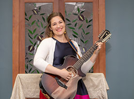 A woman holding a guitar and smiling. Links to Gifts by Will